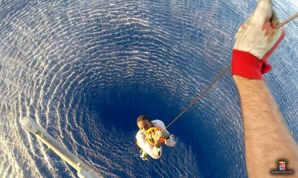 Un migrante es rescatado por un helicóptero de la marina de guerra italiana en el área donde su barco se hundió en el Mar Mediterráneo.- Armada REUTERS.