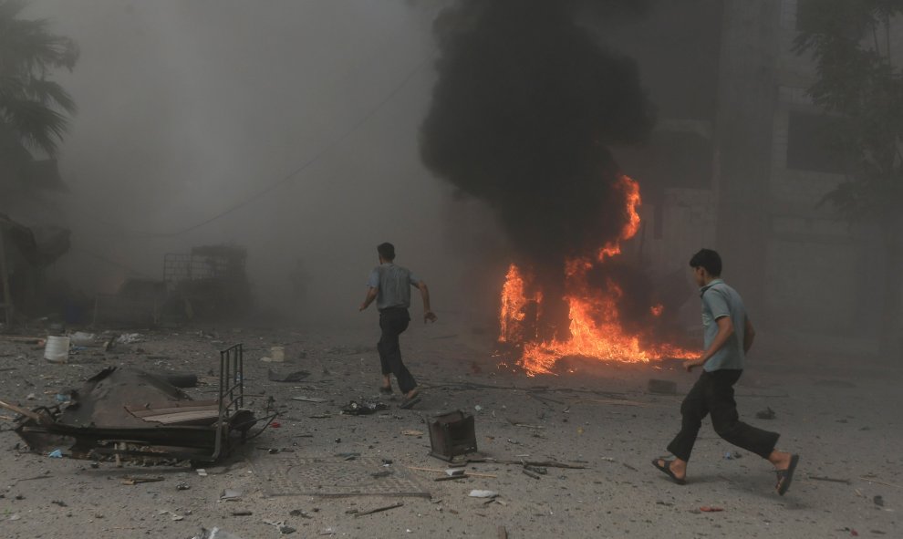 Hombres huyen del fuego ocasionado por el bombardeo efectuado por el Ejército de Bashar Al-Assad./ REUTERS