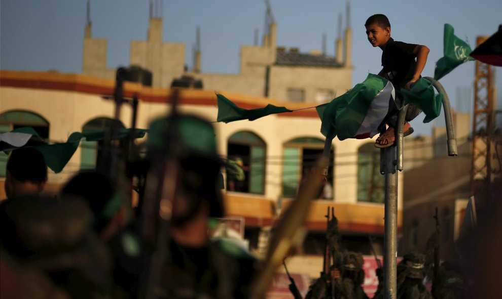 Un niño palestino mira a militantes de Hamas durante un desfile militar que marca el primer aniversario de la matanza de los comandantes militares de Hamas Abu Shammala y al- Attar en Rafah, en el sur de la Franja de Gaza. REUTERS
