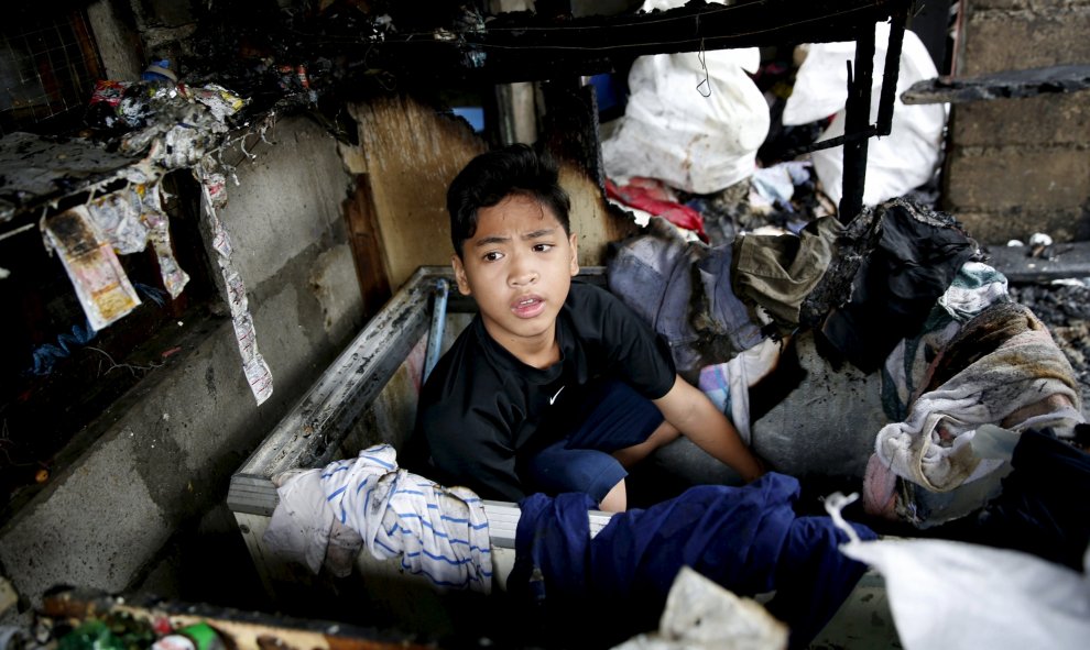 Un niño se recupera ropa escondida en un congelador después de un incendio en un barrio residencial en Paranaque,Filipinas. REUTERS