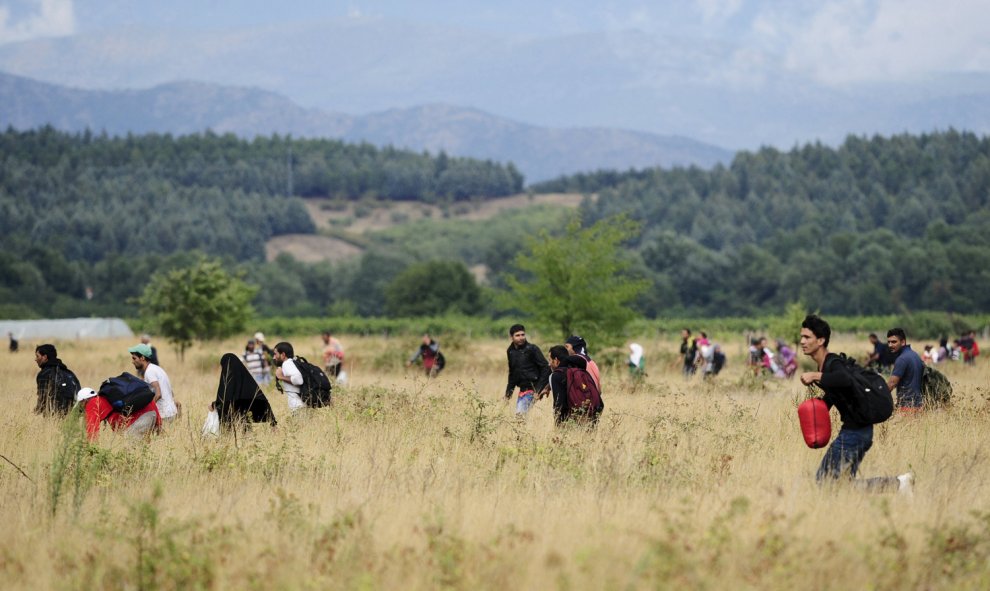 Los refugiados que rompen el cordón corren en los campos de territorio de Macedonia hacia la ciudad de Gevgelija, donde cogerán un tren a Serbia.- REUTERS/Ognen Teofilovski