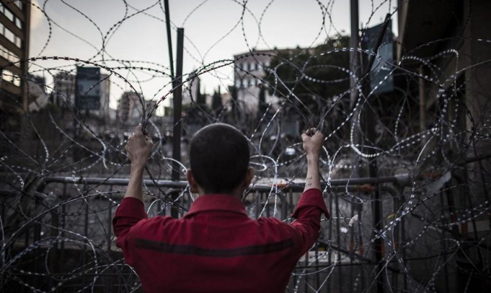 Un hombre agarra el alambre de espino que bloquea el acceso a la sede del Gobierno en Beirut, Líbano, hoy 26 de agosto de 2015. En los últimos días, miles de personas han salido a las calles de la capital del país para protestar por la crisis de la recogi