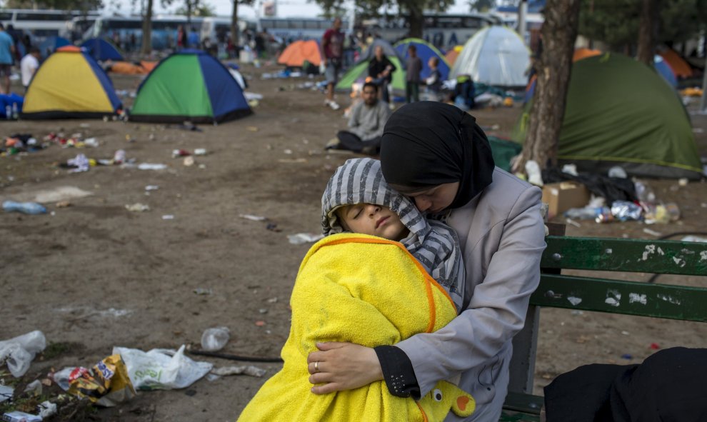 Una refugiada siria sujeta a su hijo mientras duerme en un parque con un niño duerme en un parque cerca de la principal estación de autobuses y de tren en Belgrado, Serbia, después de días caminando desde Macedonia para llegar al norte de Europa.- REUTERS