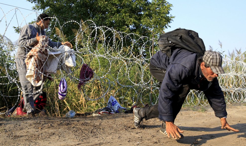 Un refugiados sirio gatea después de cruzar por debajo de una cerca de cuchillas para entrar en Hungría desde Serbia, cerca Röszke. Austria será su próximo destino.- REUTERS / Bernadett Szabo
