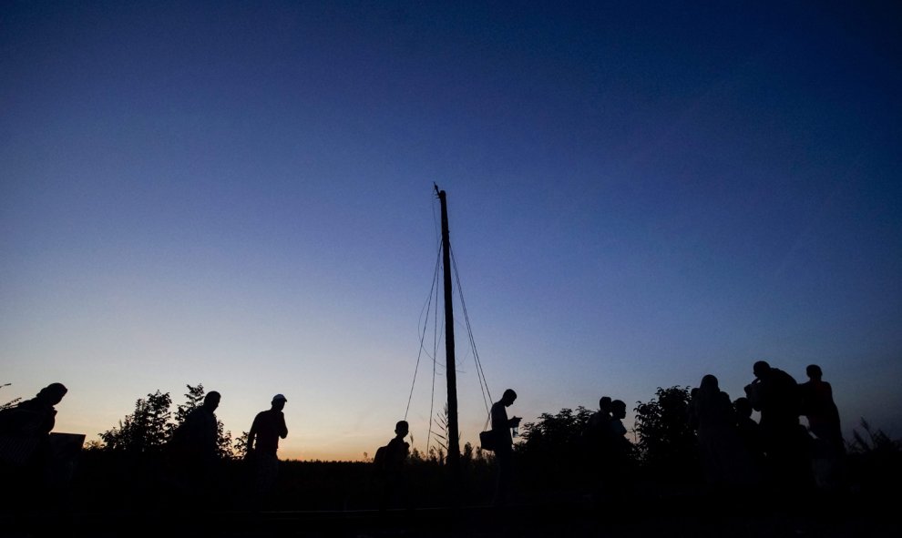 Varios refugiados caminan por la línea férrea, cerca de Roszke, Hungría, para cruzar su frontera con Serbia.- EFE/Zoltan Balogh