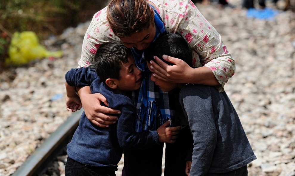 Una mujer abraza a dos niños después de cruzar la frontera de Grecia a Macedonia.- OGNEN TEOFILOVSKI (REUTERS)