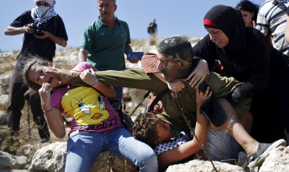 Palestinos se pelean con un soldado israelí en su intento de evitar que la detención de un niño, durante una protesta contra los asentamientos judíos en la aldea cisjordana de Nabi Saleh, cerca de Ramallah. REUTERS