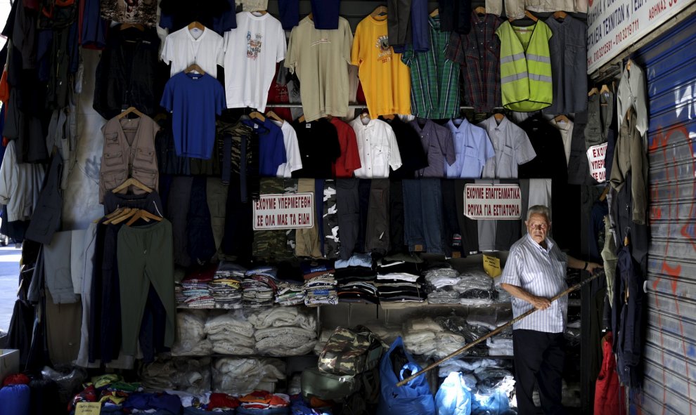 Tendero arregla la ropa fuera de su tienda en el centro de Atenas. REUTERS