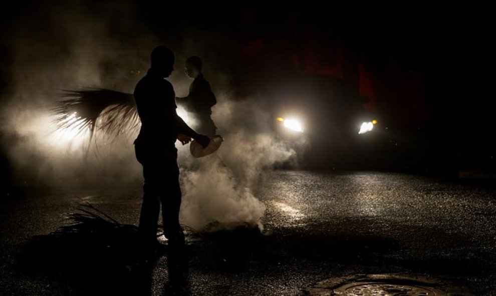 Policías dominicanos apagan una barricada encendida en protesta por el extenso apagón, debido a que el 85% del país se encuentra sin energía eléctrica tras el paso de la tormenta tropical Erika hoy, viernes 28 de agosto de 2015, en la zona colonial de San