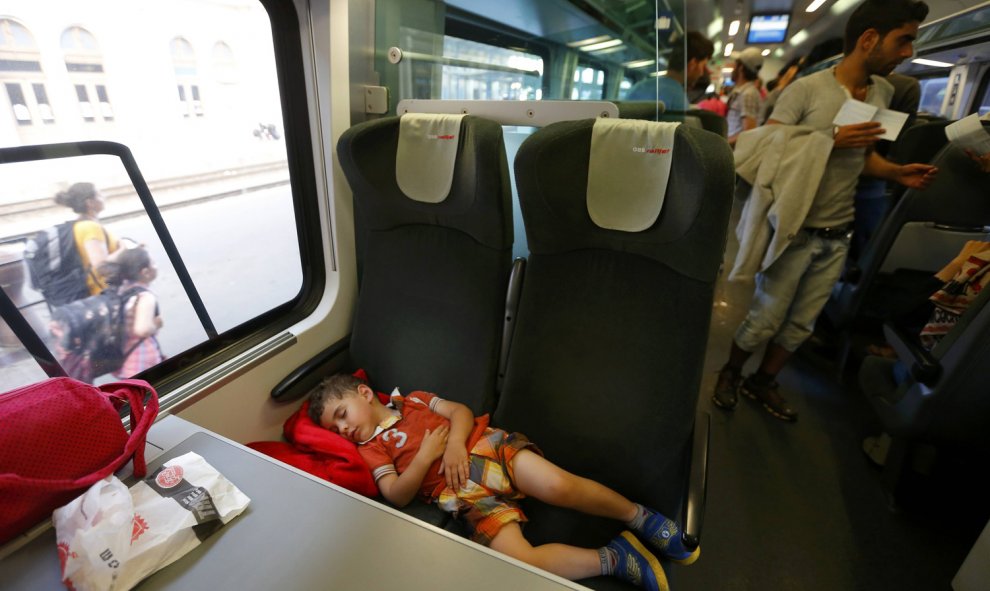Un niño duerme en los asientos del tren a la espera de que el convoy parta con destino a Austria y Alemania. REUTERS