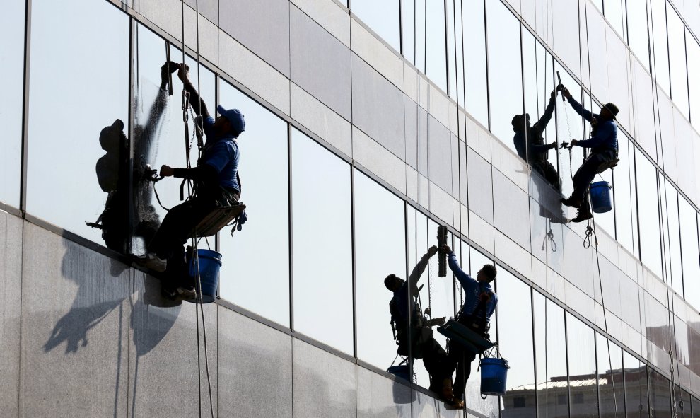 Varios trabajadores limpian los cristales de un edificio de oficinas en Washington, 1 de septiembre de 2015. REUTERS/Kevin Lamarque