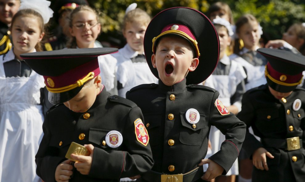 Niños en Ucrania celebran en un acto la vuelta al cole. En la foto, un niño vestido con traje bosteza./ REUTERS/Gleb Garanich