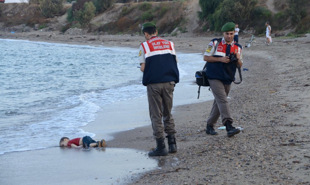 Dos agentes de la gendarmería turca, junto al cadaver de un niño que formaba parte del grupo de refugiados sirios que naufragaron intentando llegar a la isla de Kos. REUTERS/Nilufer Demir