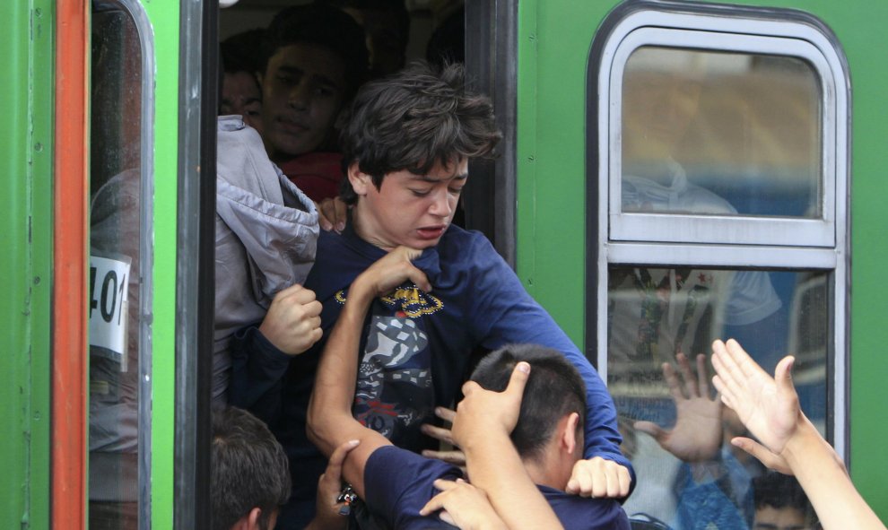Un niño pelea contra los que intentan también acceder a uno de los trenes en Budapest. /REUTERS