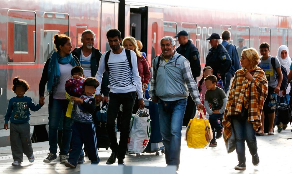 Varios refugiados caminan junto a un tren en la estación principal de Múnich. A mediados de la tarde habían llegado a la ciudad alemana cerca de 850 refugiados en varios trenes procedentes de Hungría.- MICHAEL DALDER (REUTERS)