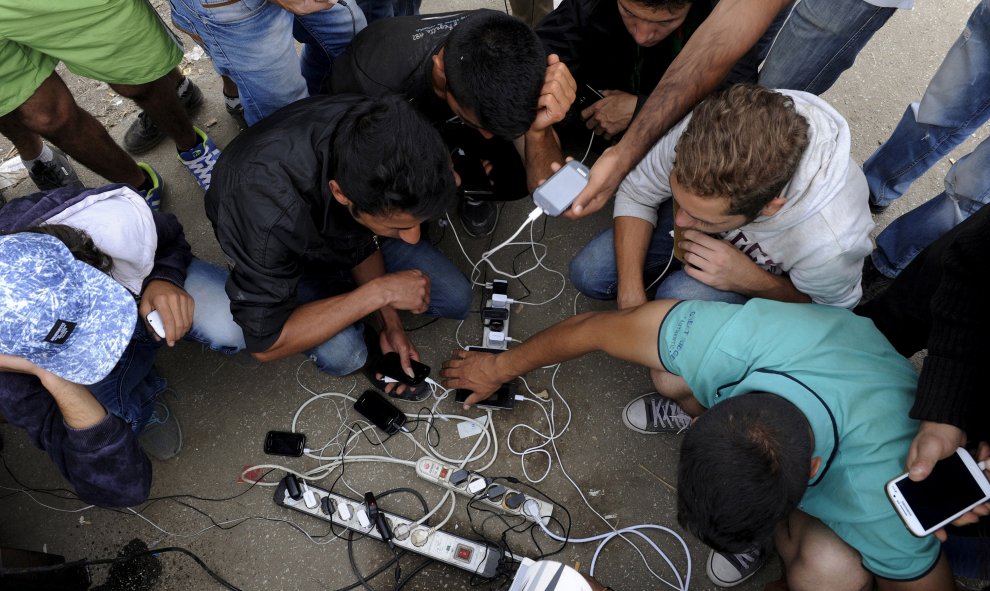 Cargan sus teléfonos móviles mientras esperan para cruzar la frontera de Grecia con Macedonia, cerca del pueblo de Idomeni, 6 de septiembre de 2015. REUTERS / Alexandros Avramidis