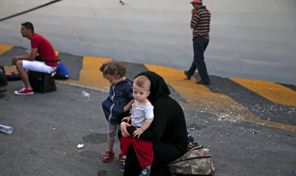 Una refugiada siria sostiene a su hijo mientas espera a subirse a un autobús después de su llegada a bordo del buque de pasajeros Tera Jet en el puerto de El Pireo, cerca de Atenas, Grecia 6 de septiembre de 2015. REUTERS / Alkis Konstantinidis