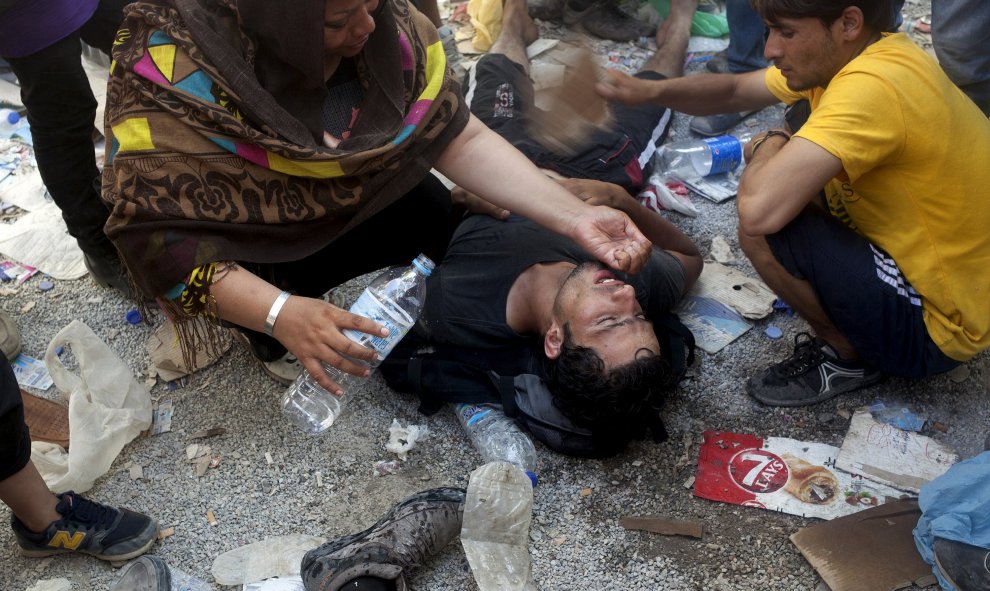 Ayudan a un hombre después de desmayarse por el calor tras los enfrentamientos en el proceso de registro en el puerto de Mitilene, en la isla griega de Lesbos, 5 de septiembre de 2015. REUTERS / Dimitris Michalakis