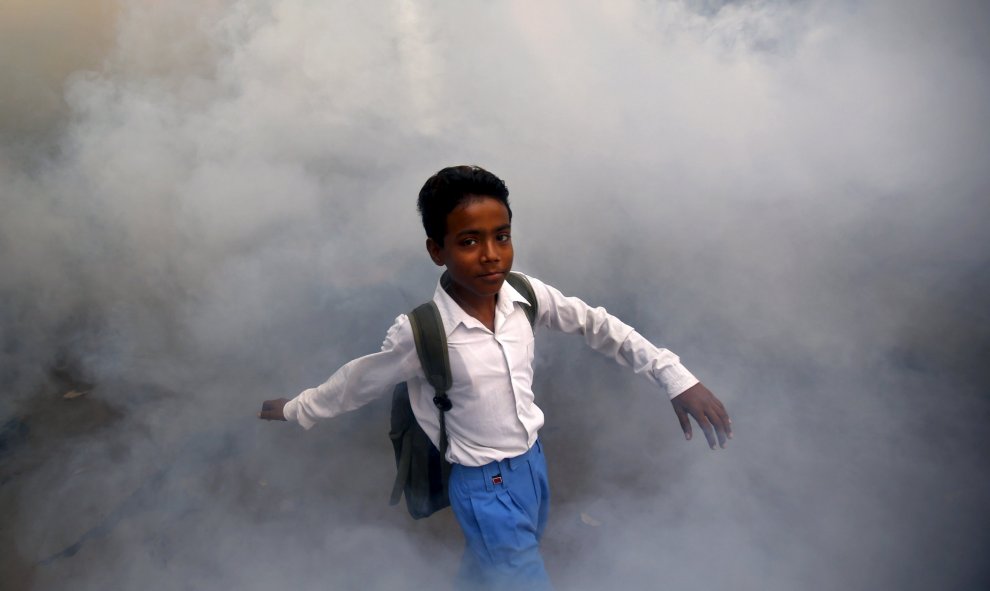 Un niño camina en medio de los gases de una fumigación realizada por un trabajador municipal en una localidad residencial en Nueva Delhi, India, 15 de septiembre de 2015. REUTERS / Anindito Mukherjee