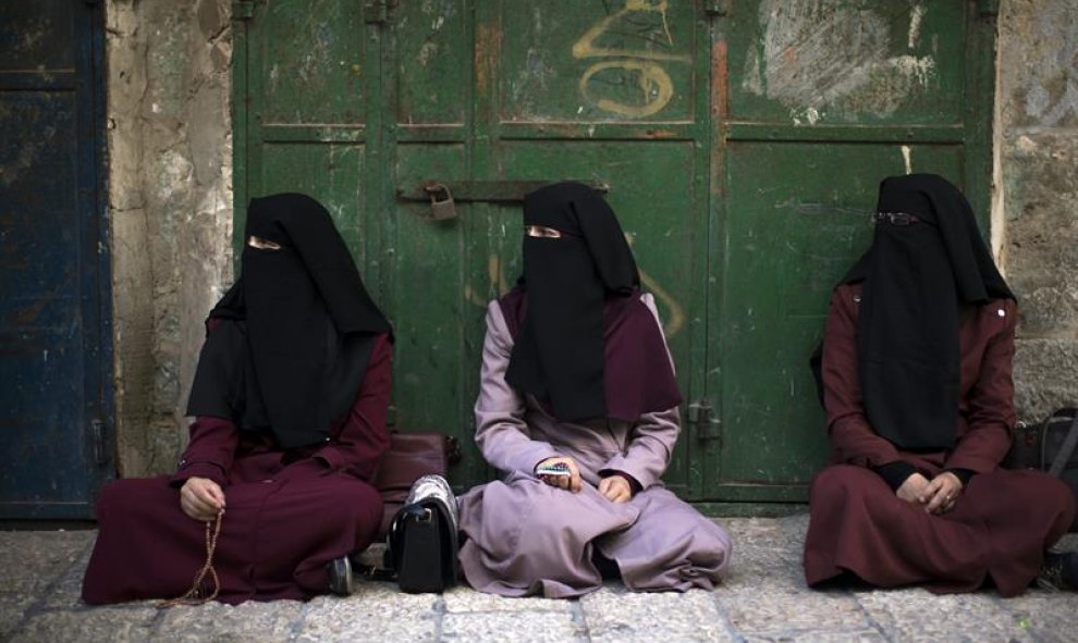 Tres activistas palestinas del grupo Murabitat (Palestinos del este de Jerusalén y Árabes israelíes) sentadas en un callejón tras ser bloqueadas por las fuerzas de seguridad israelíes. EFE/Atef Safadi