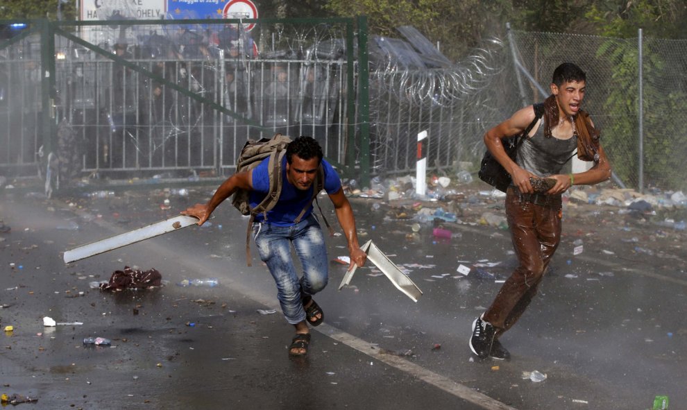 Un grupo de inmigrantes protesta en la frontera mientras la Policía húngara les rocía con gases y cañones de agua. REUTERS