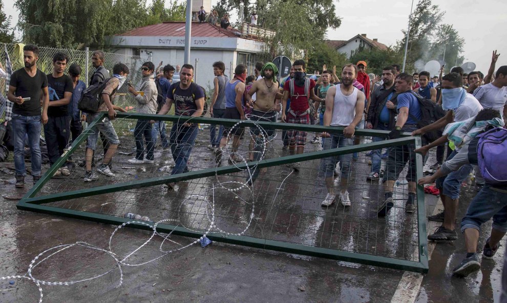 Un grupo de refugiados sostiene la puerta de la valla fronteriza con Hungría tras arrancarla. REUTERS