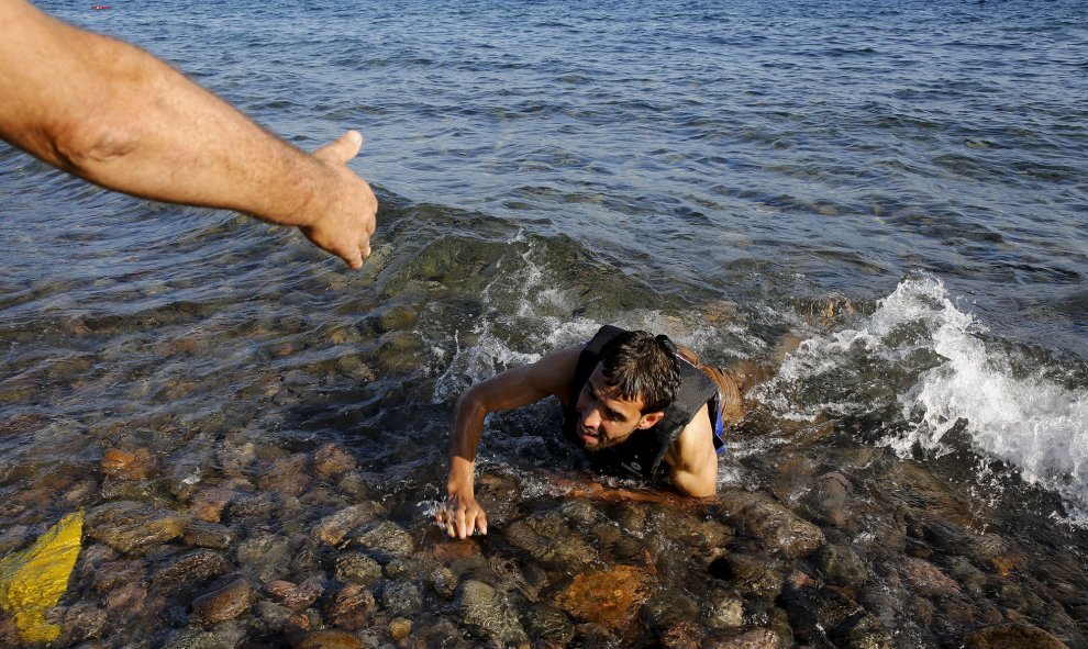 Un hombre ayuda a un refugiado sirio que nadó hasta la orilla desde el bote en la costa de Lesbos, 17 de septiembre, 2015. REUTERS/Yannis Behrakis