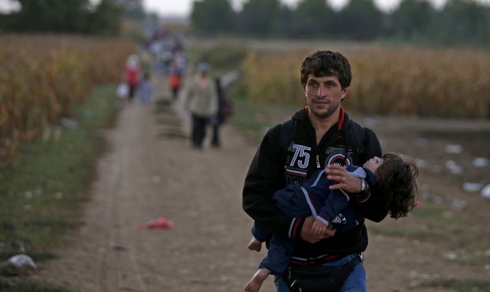 Un refugiado lleva a una niña en brazos cerca de la frontera de Croacia. REUTERS