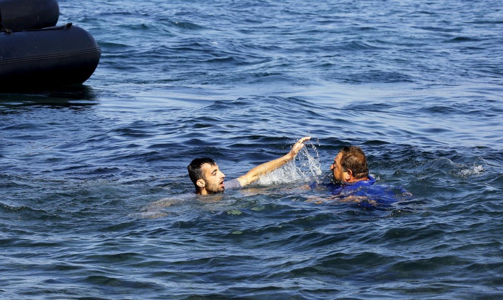 Un voluntario griego se tira al agua tras él también sin chaleco salvavidas para salvarle./ EUROPA PRESS
