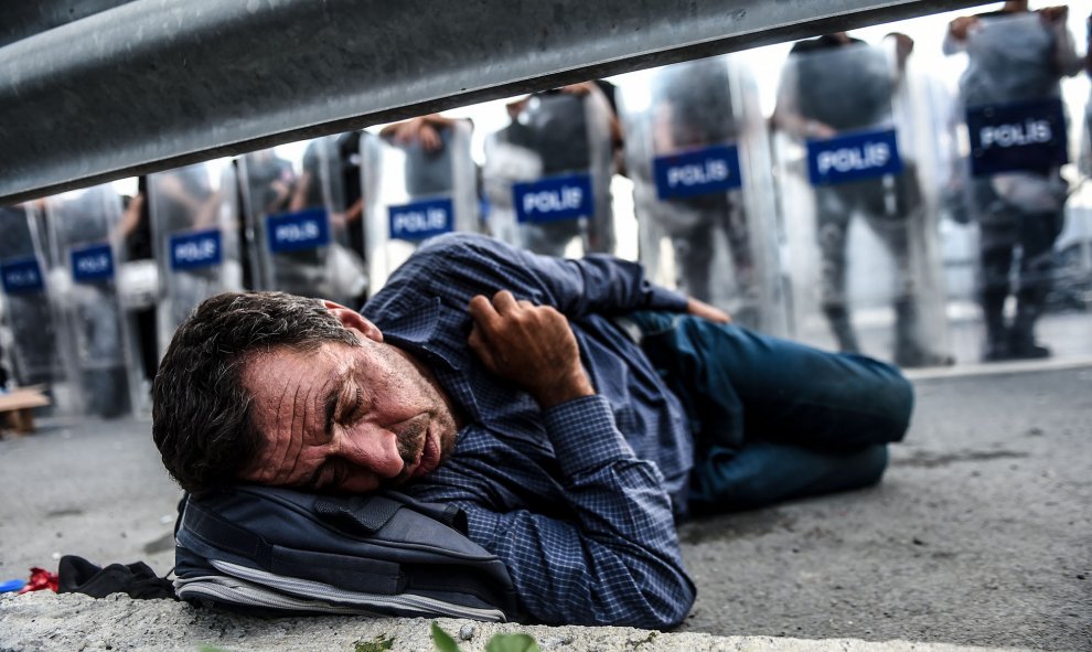 Un migrante descansa delante de una barricada de la policía después que los antidisturbios turcos bloquearan la carretera en dirección a Edirne, el 21 de septiembre de 2015, de Estambul. AFP PHOTO / OZAN Kose