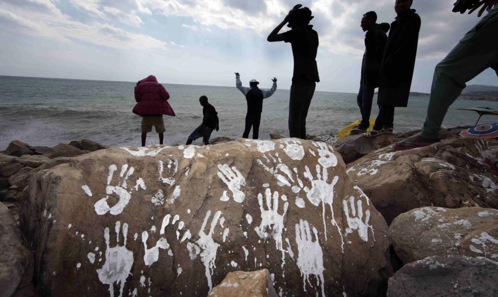 Un grupo de emigrantes sudaneses y eritreos cerca de una roca con impresiones blancas de manos en el cruce fronterizo de San Ludovic, en el mar Mediterráneo entre Vintimille, Italia y Mentón, Francia. REUTERS / Eric Gaillard