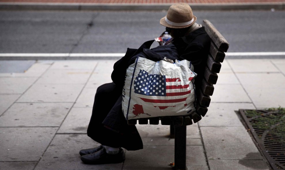 Una mujer sin hogar descansa en un banco a pocos metros de la Casa Blanca en Washington. CARLOS BARRIA (AFP)