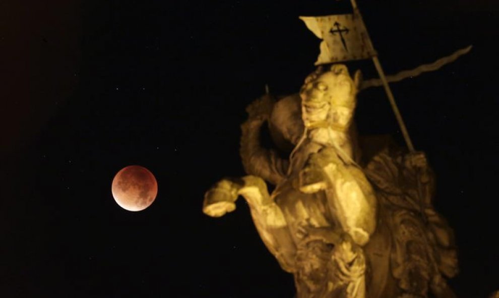 Fotografía de un eclipse total de luna visto junto a una escultura del apóstol Santiago a caballo en la madrugada de hoy, lunes 28 de septiembre de 2015, cerca al ayuntamiento de Santiago de Compostela (España). EFE/Lavandeira jr