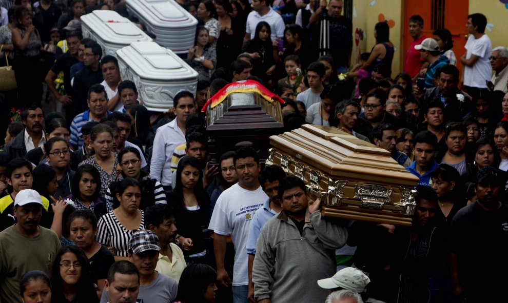 Amigos y familiares cargan los ataúdes de cinco personas que murieron en el deslave en Santa Catarina Pinula (Guatemala). Siguen las labores de búsqueda de las 300 personas desaparecidas por un alud que arrasó con un asentamiento y que produjo al menos 11