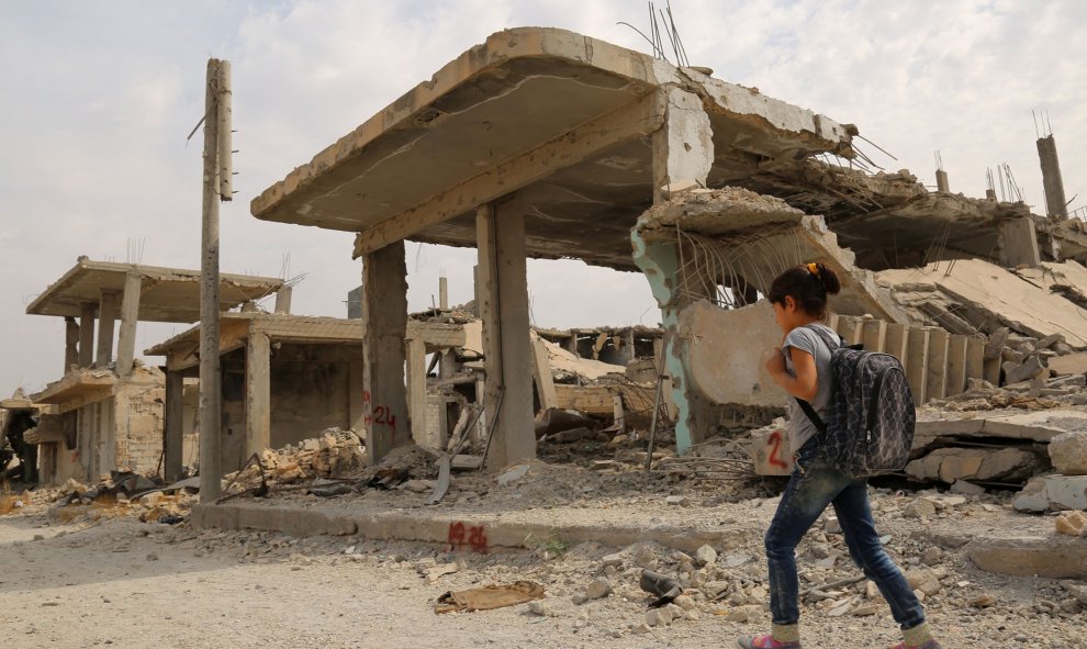 Los niños sirios caminan al lado de los escombros en su camino al colegio en el segundo día del nuevo año escolar, el 6 de octubre de 2015, en la ciudad kurda de Siria de Kobane. AFP PHOTO / delil Souleiman