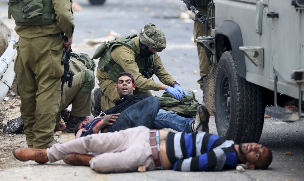 Soldados israelíes detienen a manifestantes palestinos heridos durante enfrentamientos cerca del asentamiento judío de Bet El, cerca de la ciudad cisjordana de Ramala, 7 de octubre de 2015.REUTERS / Mohamad Torokman