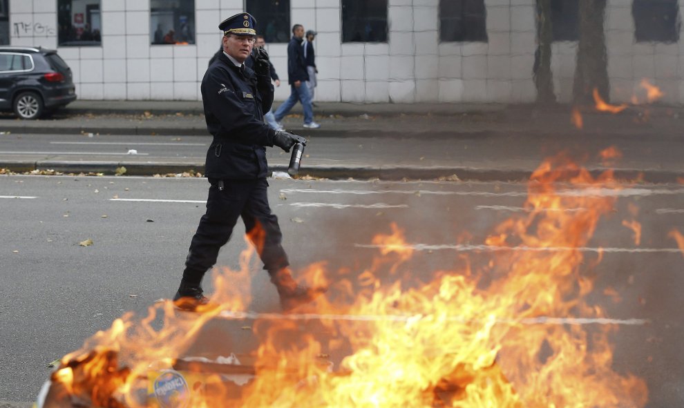 Un policía trata de apagar las llamas causadas durante los disturbios en Bruselas, Bélgica.- EFE/Laurent Dubrule