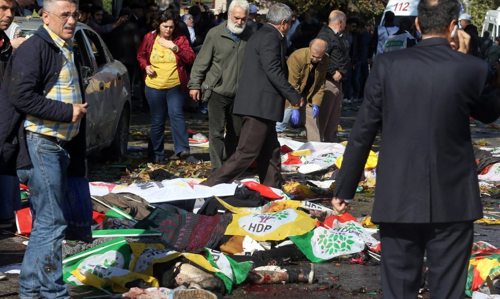 Varias personas cubren con banderas y pancartas a las víctimas mortales provocadas por los atentados en centro de Ankara durante una marcha pro-kurda. EFE/EPA/STR