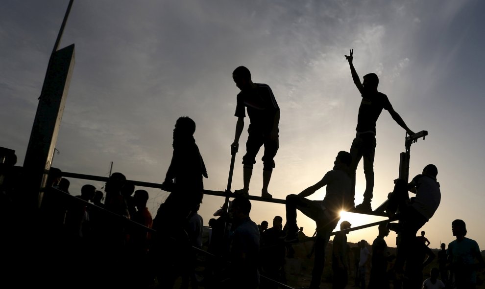 Manifestantes palestinos se sitúan en la valla fronteriza durante los enfrentamientos con las tropas israelíes cerca de la frontera entre Israel y el centro de la Franja de Gaza 13 de octubre de 2015. REUTERS / Ibraheem Abu Mustafa