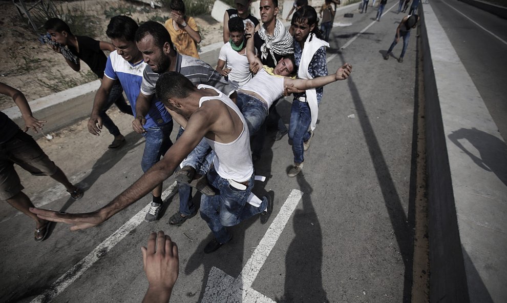 Jóvenes palestinos trasladan a un compañero herido durante un enfrentamiento con soldados israelíes cerca del cruce de Erez, en el norte de la Franja de Gaza, Palestina. EFE/Mohammed Saber