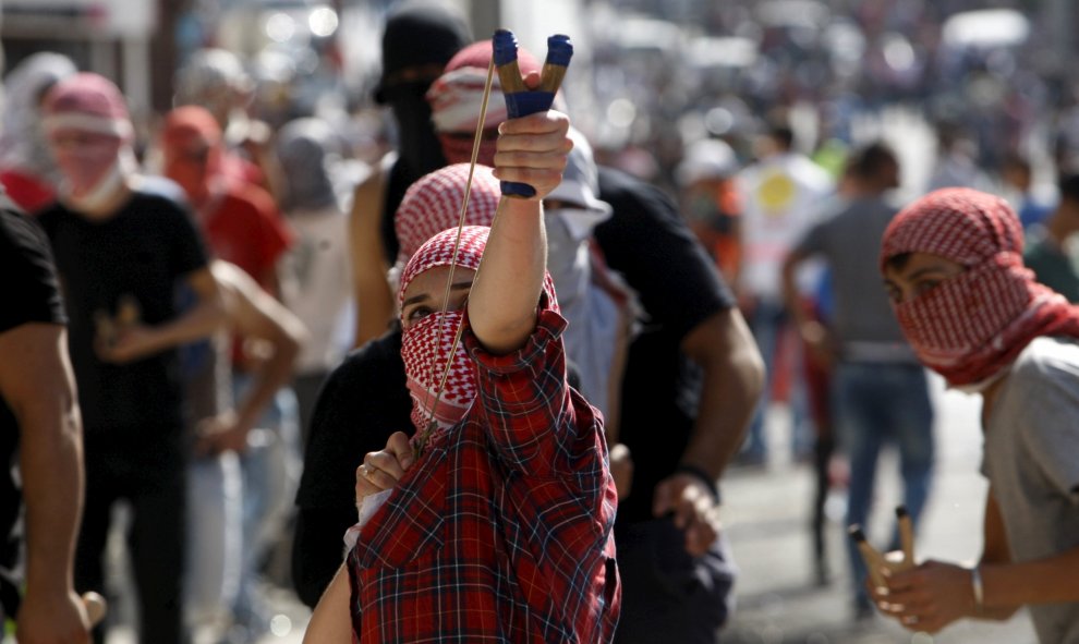 Una chica palestina utiliza un tirachinas para lanzar piedras a los soldados israelíes durante los enfrentamientos en la ciudad cisjordana de Belén, 14 de octubre de 2015. REUTERS / Mussa Qawasma