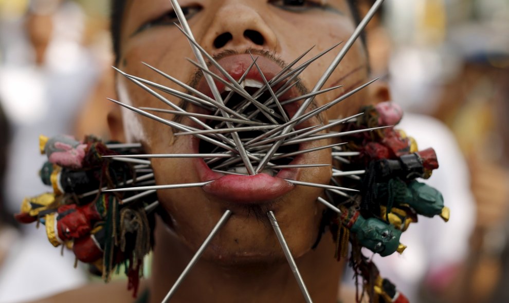 Un devoto del santuario chino Samkong  camina con agujas que le atraviesan las mejillas durante una procesión que celebra el festival anual vegetariano en Phuket, Tailandia, 16 de octubre de 2015. REUTERS / Jorge Silva