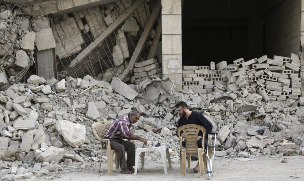 Dos hombres juegan al ajedrez enfrente de las ruinas de un edificio en la zona controlada por los rebeldes en Maaret al-Naaman, Idlib, Siria. REUTERS/Khalil Ashawi