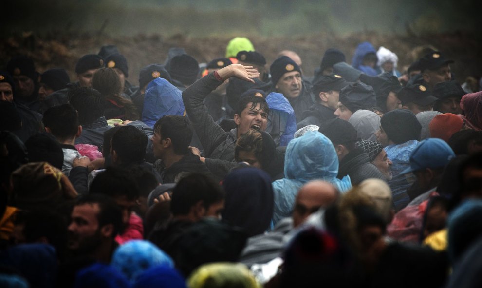 Agentes de policía croatas montan guardia mientras los emigrantes esperan para entrar en Croacia desde la frontera entre Serbia y Croacia, cerca del pueblo de Berkasovo, el 19 de octubre de 2015. AFP/ANDREJ ISAKOVIC