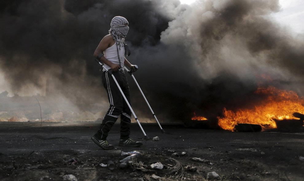 Un manifestante palestino camina con muletas durante los enfrentamientos con las tropas israelíes cerca del asentamiento judío de Bet El, cerca de la ciudad cisjordana de Ramala. REUTERS / Ammar Awad