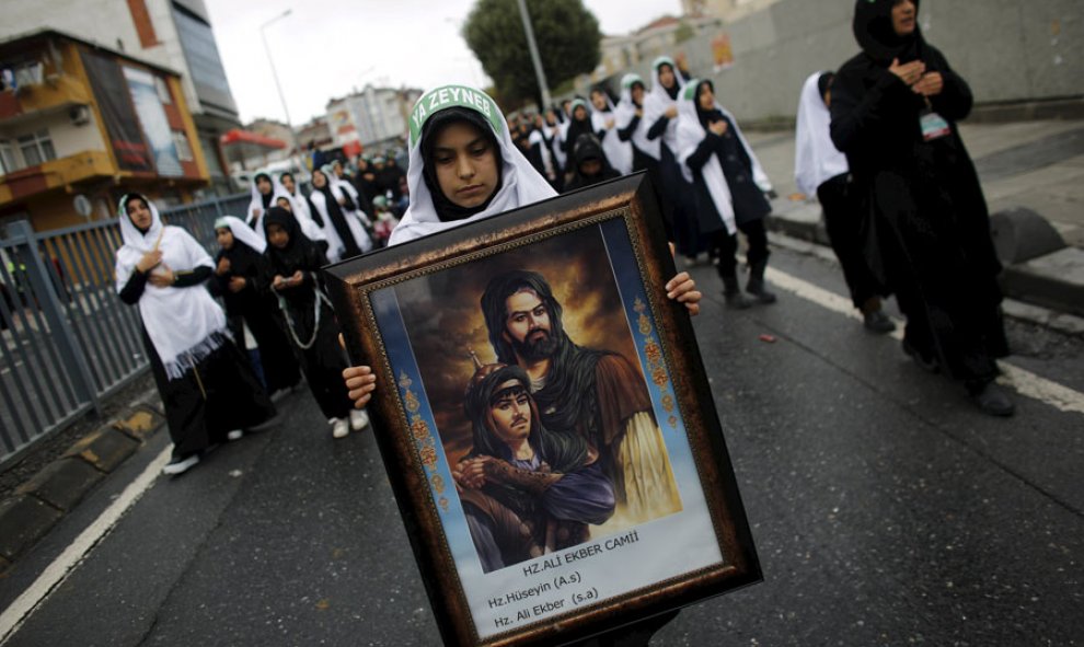 Una mujer lleva un cuadro con ilustraciones de santos islámicos durante una procesión en Estambul. REUTERS/Murad Sezer