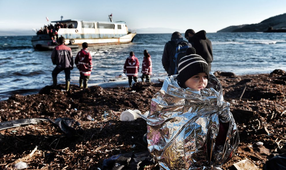 Un niño intenta entrar en calor con una manta al llegar a la isla griega de Lesbos. AFP / ARIS MESSINIS