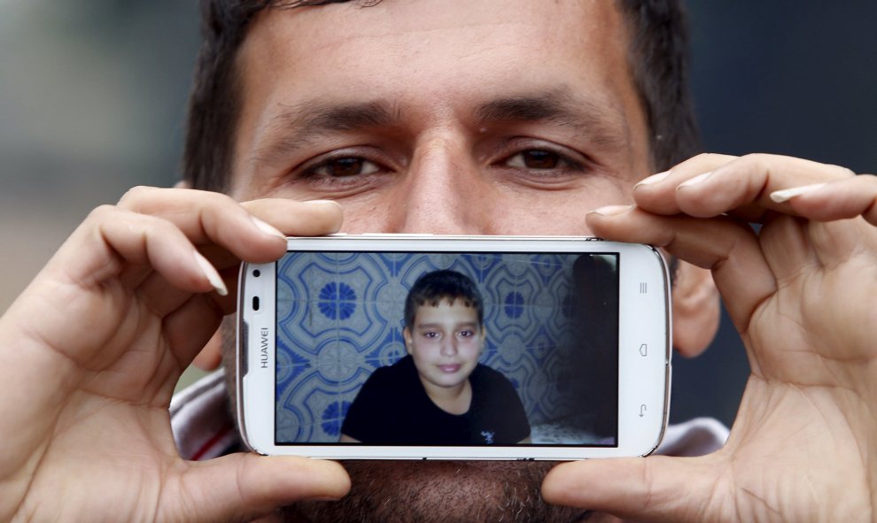 Said, de Teherán, Irán, muestra una foto de su hijo Hossein mientras espera para cruzar la frontera entre Eslovenia y Austria en Sentilj .-REUTERS / Srdjan Zivulovic