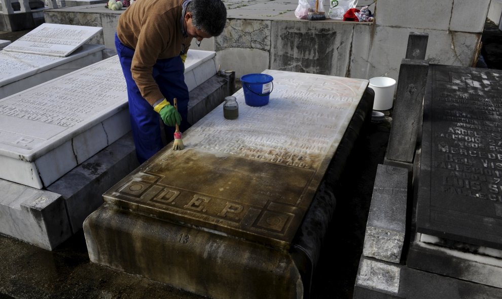 Un hombre limpia una de las tumbras del cementerio de La Carriona, en Avilés. REUTERS/Eloy Alonso