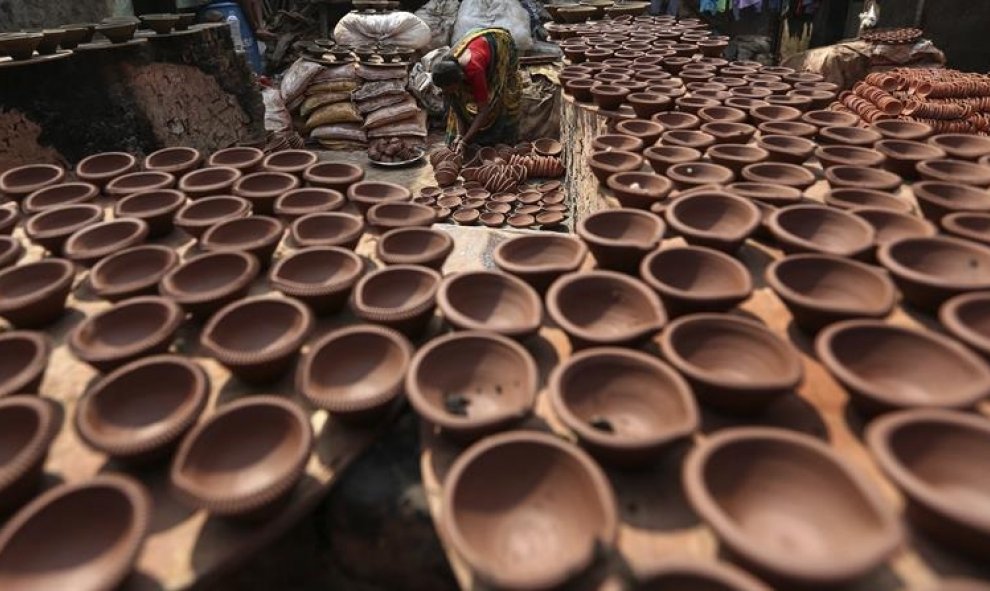 Una mujer prepara lamparillas de barro para la próxima celebración del festival Diwali en Bombay (India). EFE/Divyakant Solanki